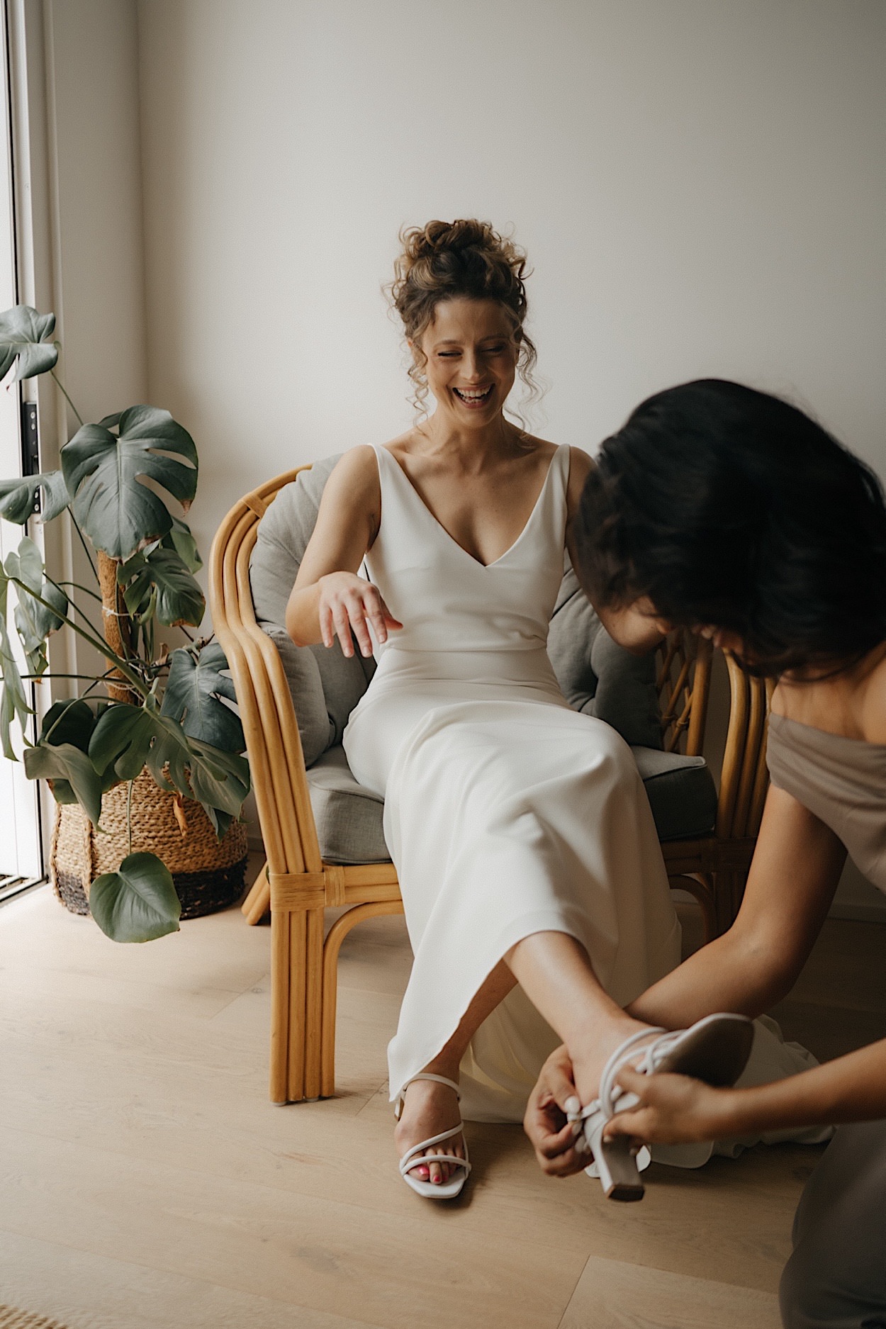 034_bridesmaid-helping-bride-before-glasshaus-brucke-wedding Bridesmaid helping the bride before the ceremony at the Glasshaus Brucke wedding in Melbourne, with the bride laughing