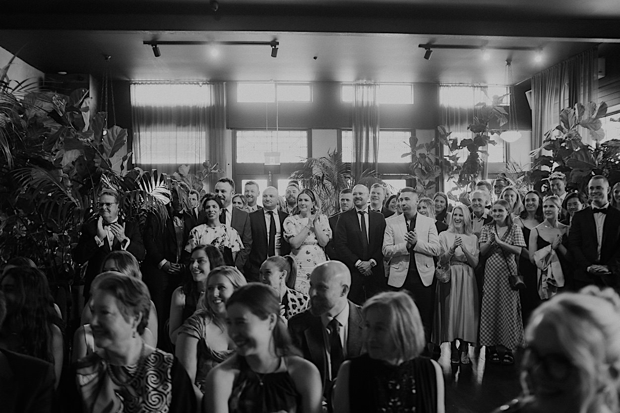 066_guests-at-glasshaus-brucke-wedding-melbourne Guests clapping as the flower men arrive at the Glasshaus Brucke wedding in Melbourne