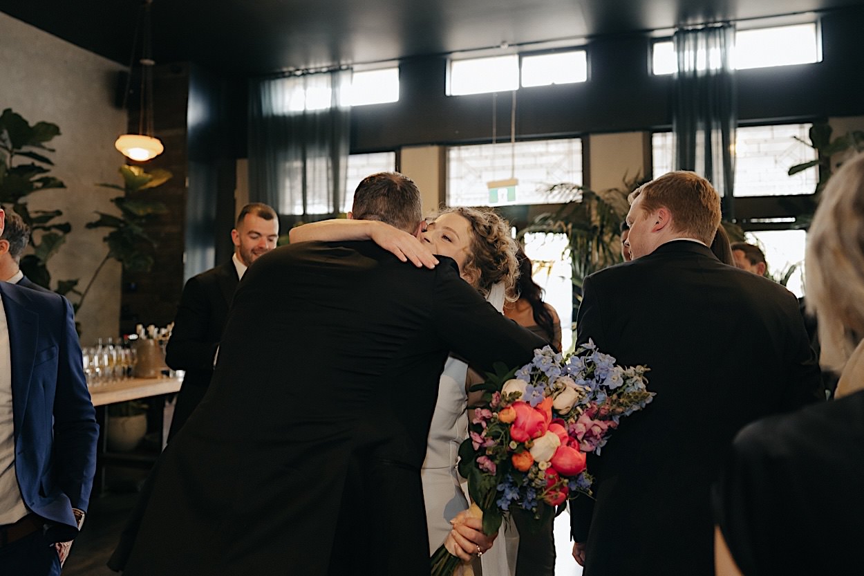 101_congratulations-glasshaus-brucke-wedding-richmond-melbourne Bride hugging a guest in celebration after the wedding ceremony at Glasshaus Brucke in Richmond, Melbourne