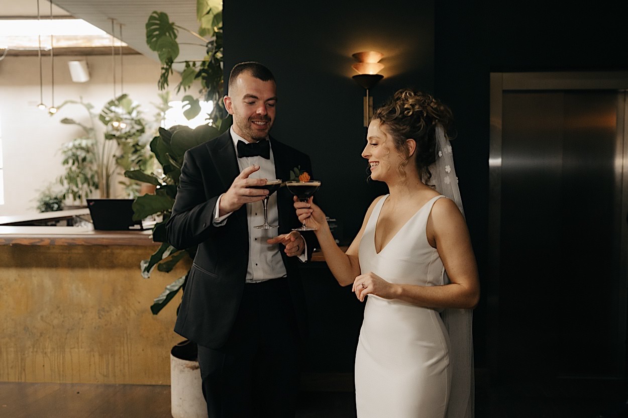 103_couple-cheers-glasshaus-brucke-wedding-melbourne Couple toasting with espresso martinis during their wedding celebration at Glasshaus Brucke in Melbourne