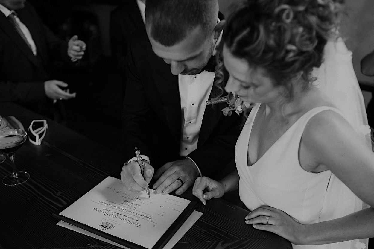 105_signing-glasshaus-brucke-wedding-richmond Close-up black and white image of the couple signing their wedding documents at Glasshaus Brucke in Richmond, Melbourne