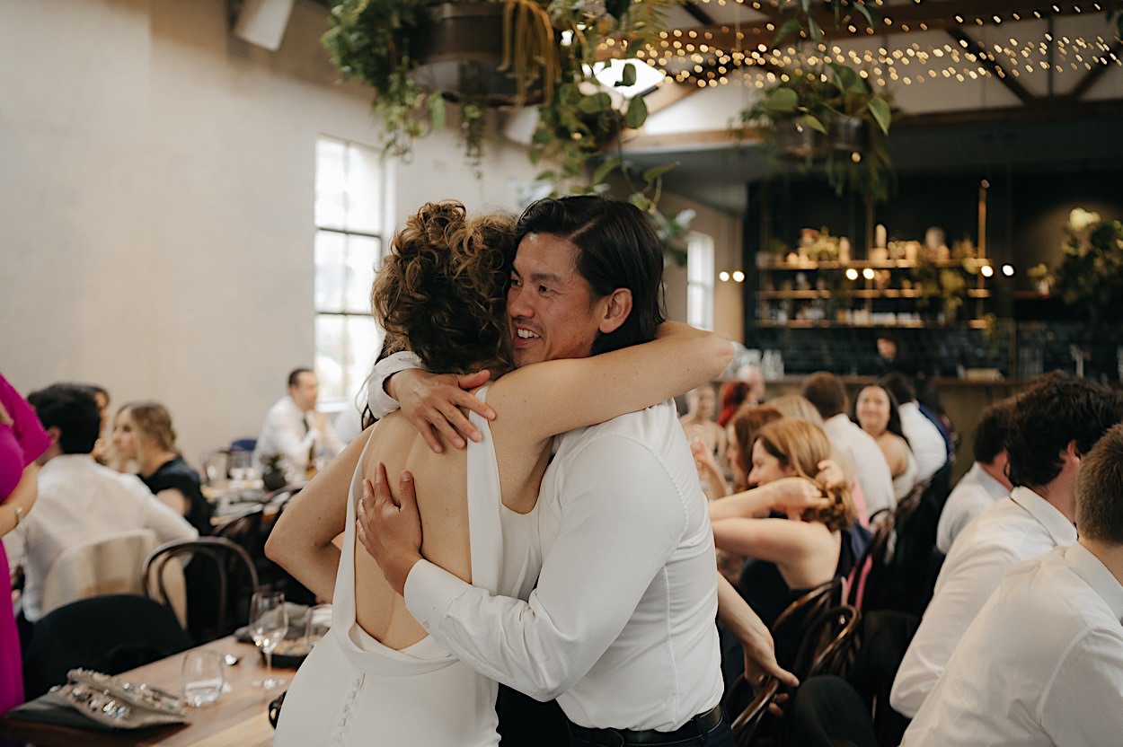 159_bride-hugging-guest-glasshaus-brucke-wedding-melbourne Bride hugging a guest at a wedding at Glasshaus Brucke in Melbourne