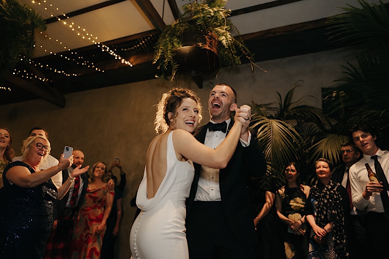 194_couple-first-dance-glasshaus-brucke-melbourne-wedding Bride and groom laughing during their first dance at a wedding at Glasshaus Brucke in Melbourne, with guests enjoying the moment