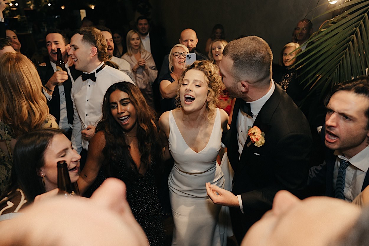 196_guests-singing-glasshaus-brucke-melbourne-wedding Guests singing with the bride and groom during their wedding at Glasshaus Brucke in Melbourne