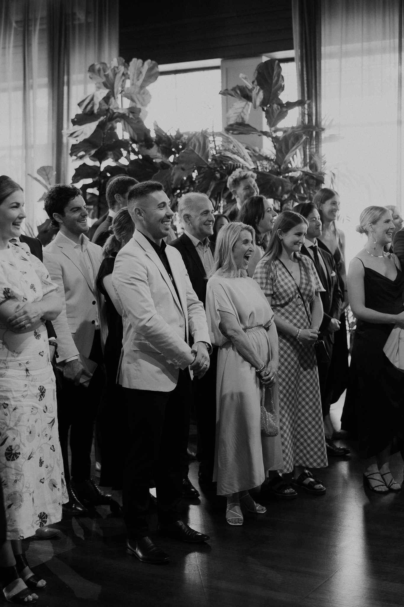 85_guests-laughing-glasshaus-brucke-ceremony-richmond Black and white photo of guests laughing during the Glasshaus Brucke wedding ceremony in Richmond