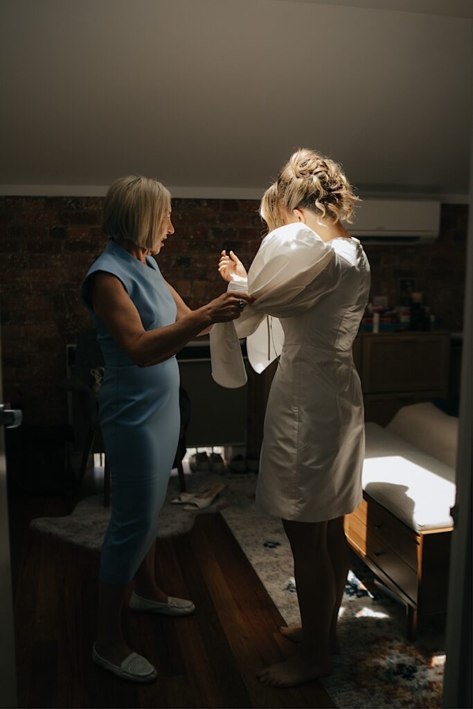 024_bride-getting-ready-before-altar-electric-wedding-melbourne Bride getting help from her mum to put on her wedding dress before the ceremony at Altar Electric, Collingwood, Melbourne
