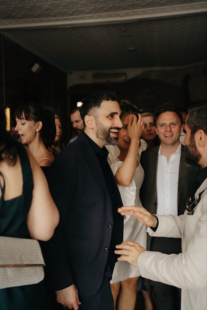 152_groom-candid-maggies-snacks-and-liquor-wedding The groom chatting with guests during the reception at Maggie’s Snacks and Liquor, smiling and engaging in conversation
