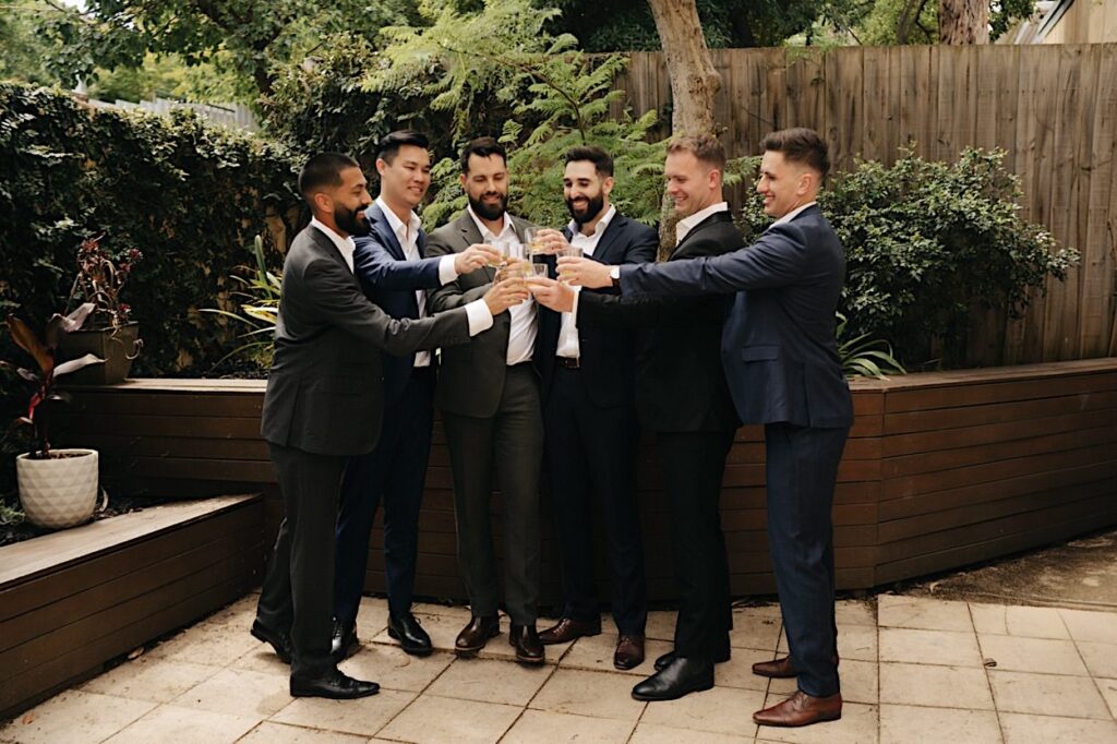 Groomsmen lined up and toasting, celebrating before the ceremony at Glasshaus Inside, Cremorne