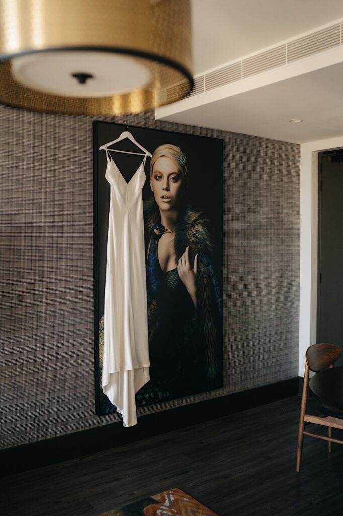 Wedding dress hanging on artwork inside the Motley Hotel before Glasshaus Inside wedding in Cremorne, Melbourne