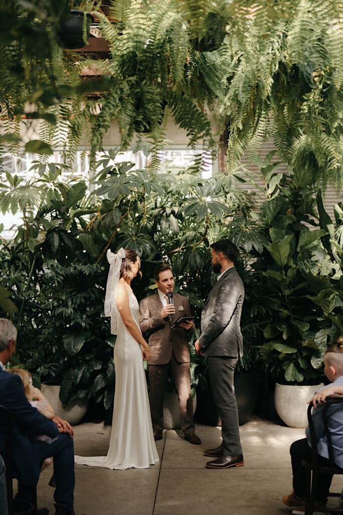 Couple standing at the front of the ceremony with celebrant Damon Hughes during their Glasshaus Inside wedding in Cremorne, Melbourne