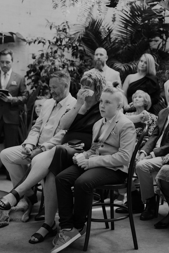 Mother of the groom wiping away tears during vows at Glasshaus Inside wedding ceremony in Cremorne