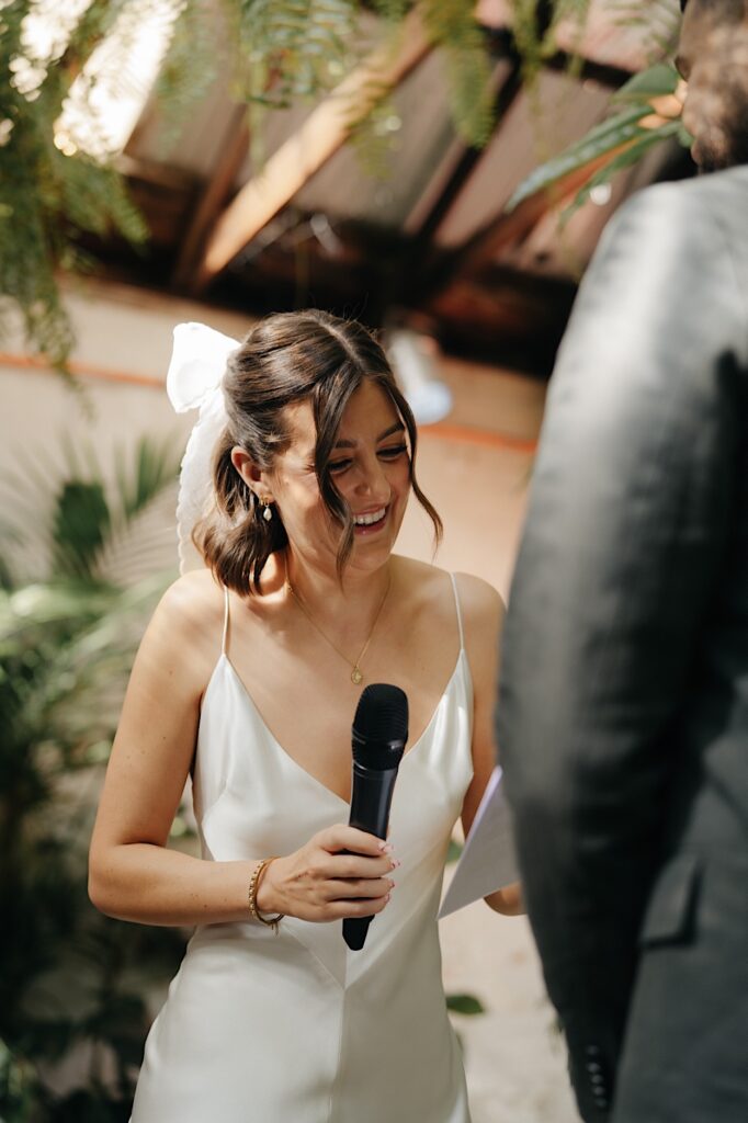 Bride laughing joyfully during her vows at Glasshaus Inside wedding ceremony