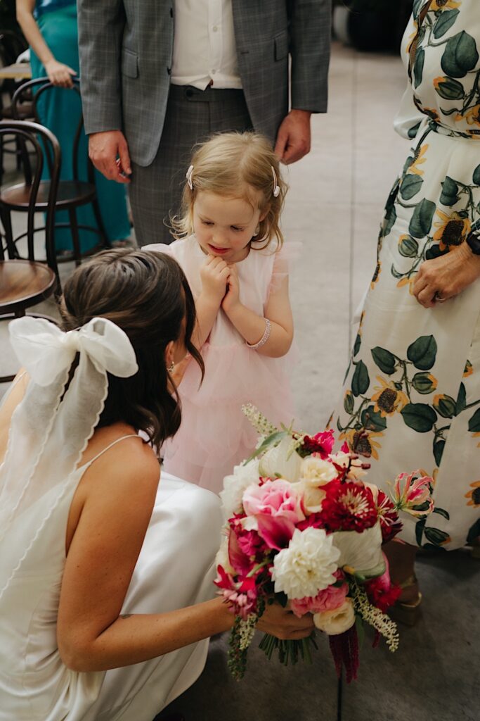 The bride crouches down to talk to the flower girl, capturing a sweet moment at a Glasshaus Inside wedding in Cremorne.