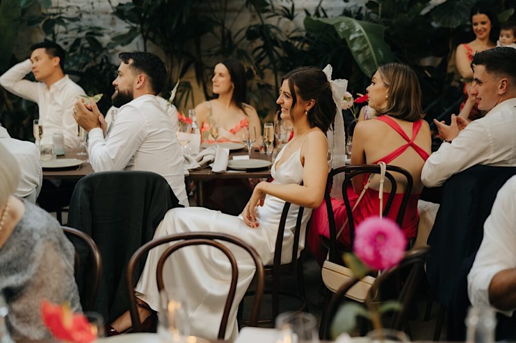 The bride and groom reacting and laughing together during a wedding speech at their Glasshaus Inside reception in Melbourne.