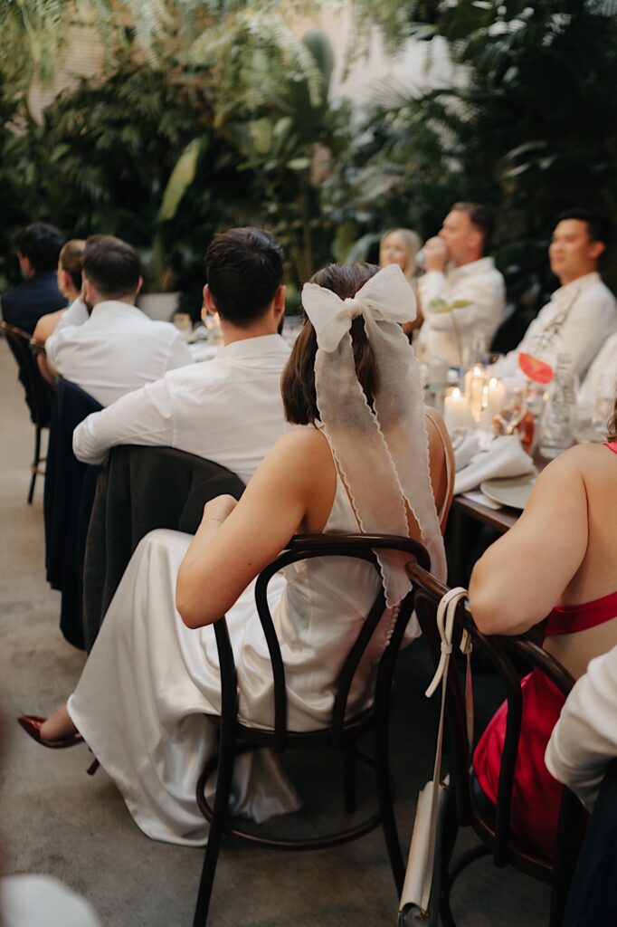 Detail of the back of the bride’s hair bow as she and the groom enjoy their Glasshaus Inside wedding reception.