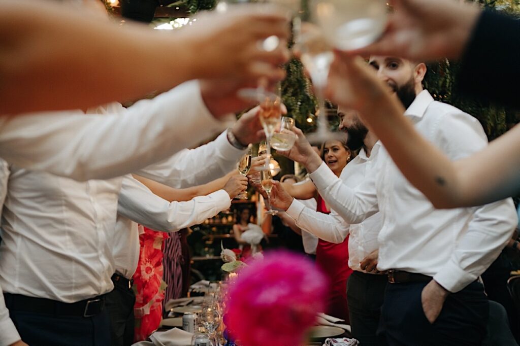 Guests clinking their glasses together in a toast during a Glasshaus Inside wedding in Cremorne, Melbourne.